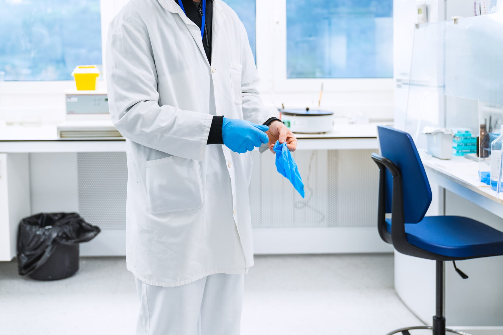 Laborfachkraft legt blaue Einmalhandschuhe an